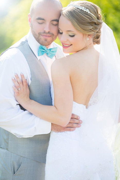 Megan and Ryan embracing outdoors, with her bouquet held close.